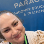 Holly Jordon, senior operations manager of paragon pet school's professional grooming certificate programs, shown in front of a tradeshow booth for paragon groomer education and training